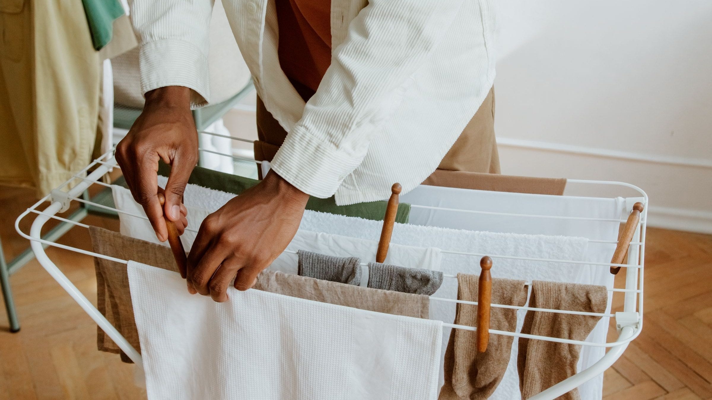 Freshly washed linens laid over an indoor drying rack in daylight