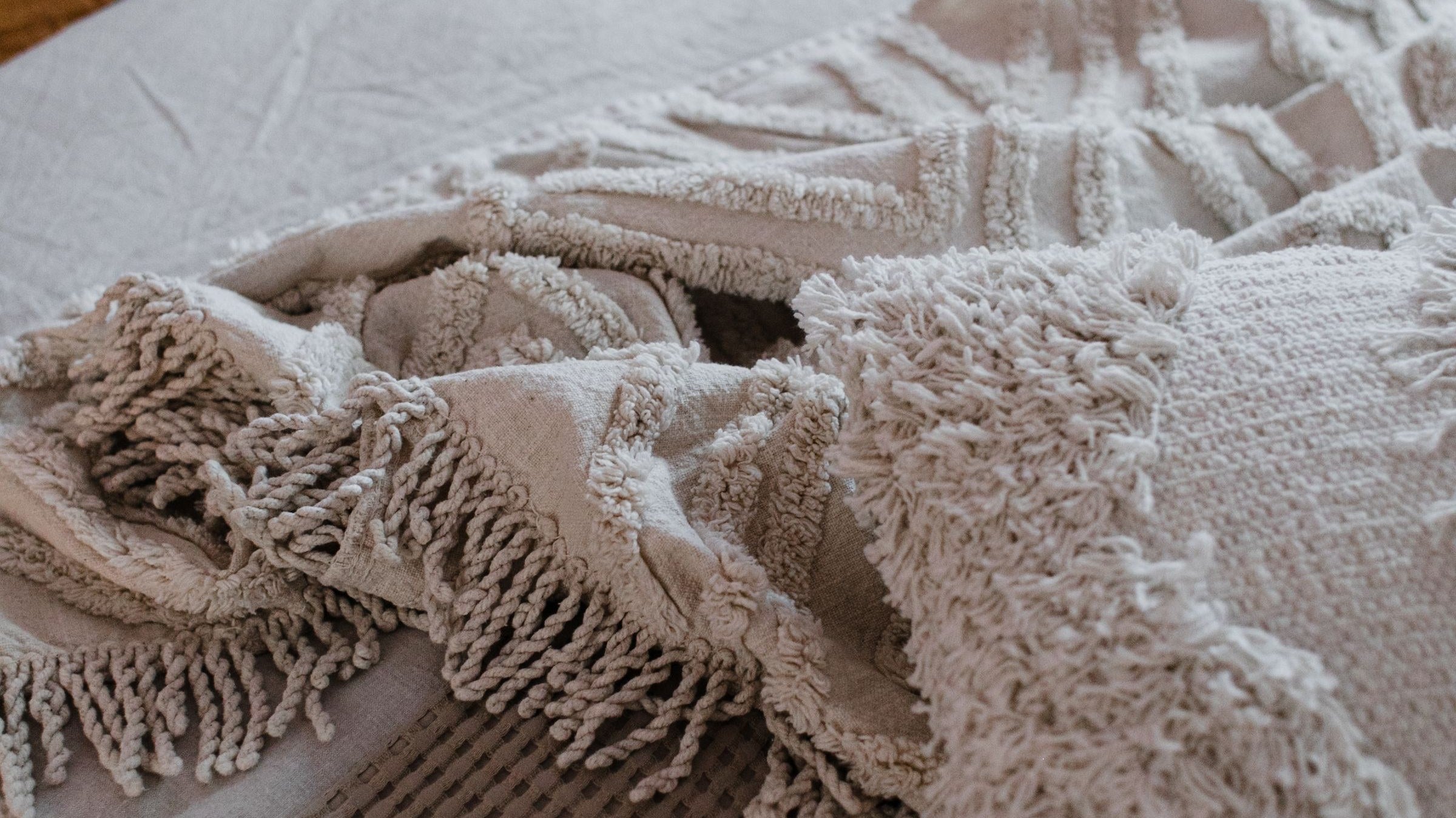 Light blankets and a throw layered across a made bed