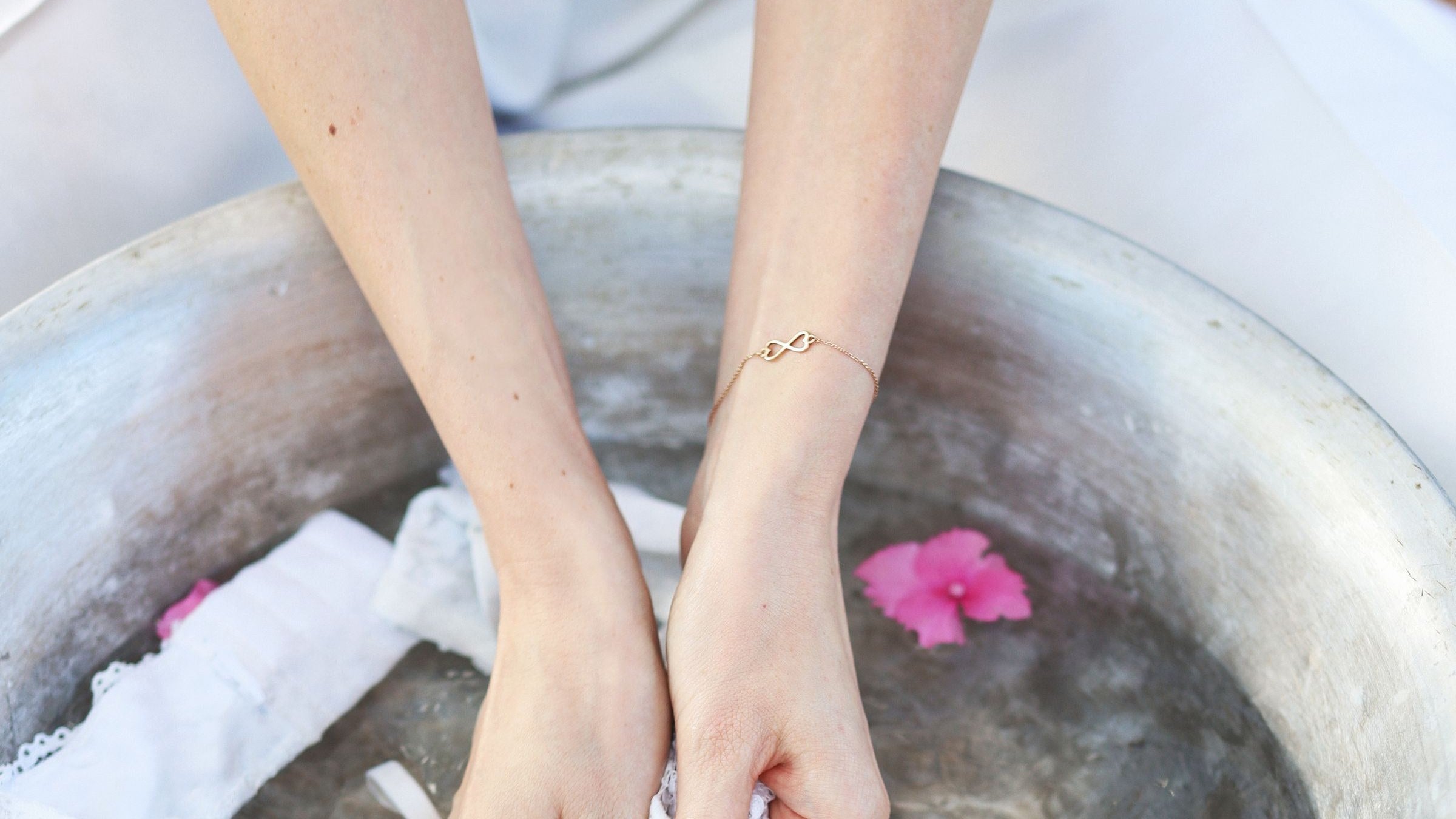 Hands washing a delicate white fabric by hand in a basin of cool water