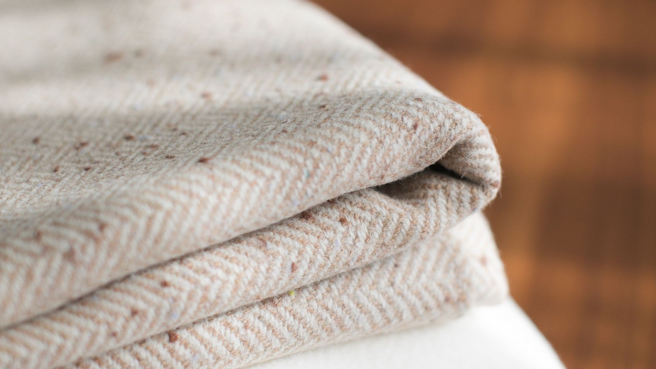 A stack of thick brushed blankets folded on a wooden table