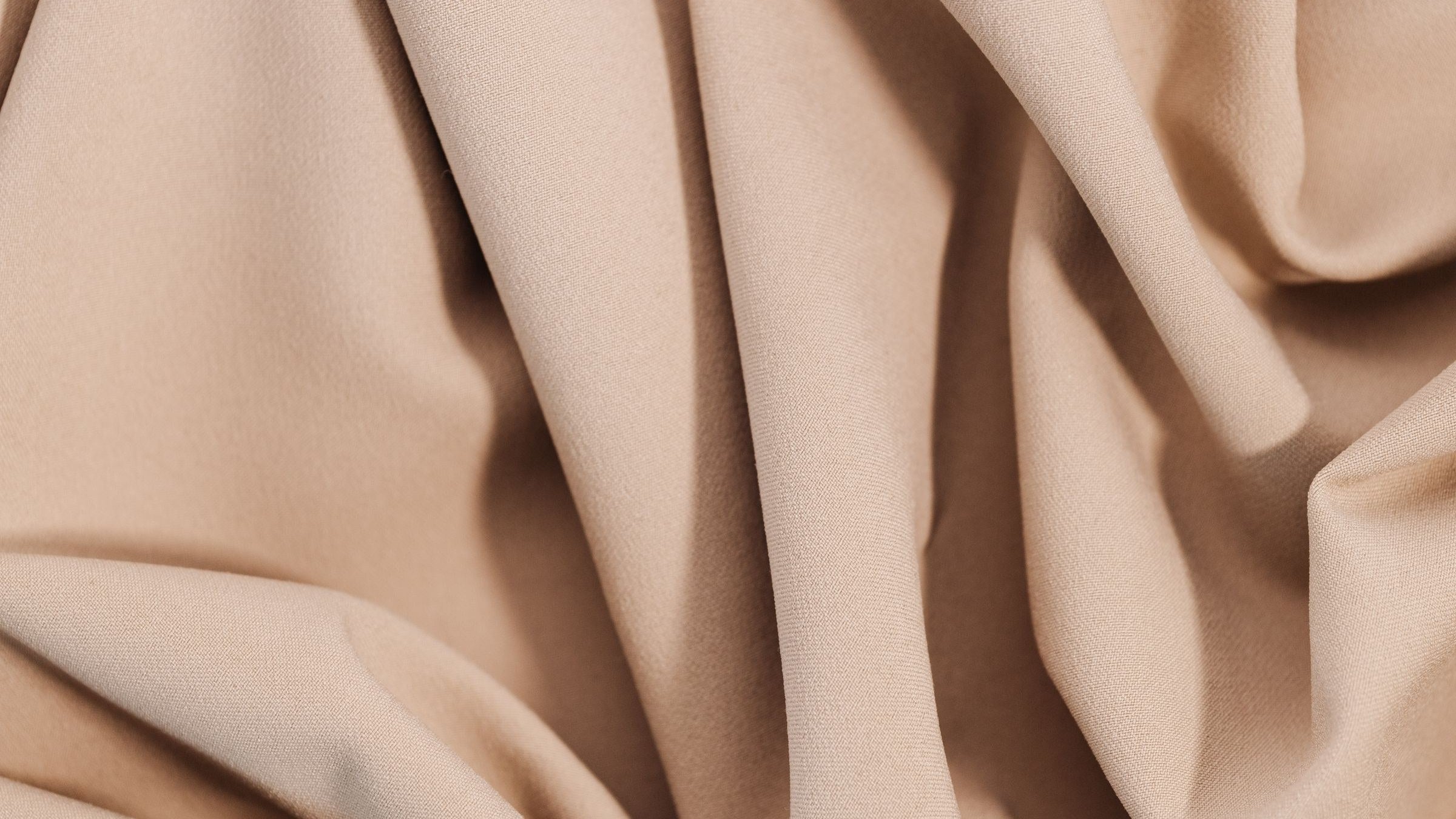 Folds of smooth beige fabric catching the light