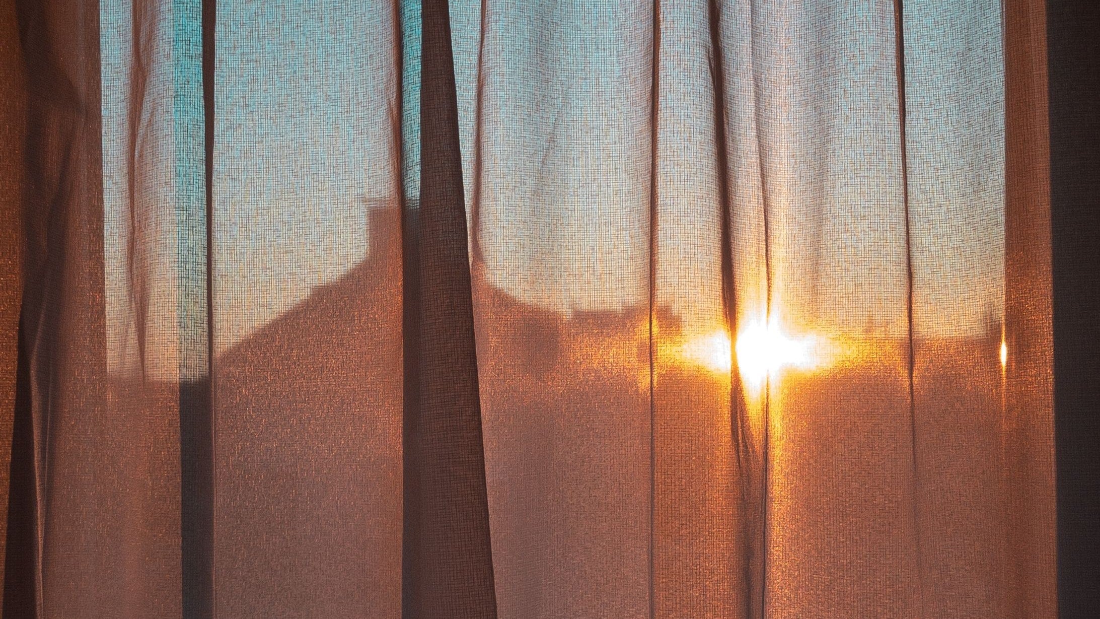 Late sun burning through a sheer curtain at a window